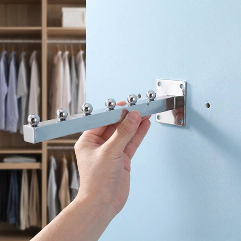Hand installing Heavy Duty Wall Mount Clothes Rack With Waterfall Hooks Four Piece Aluminum Coat Hanger System on blue wall.