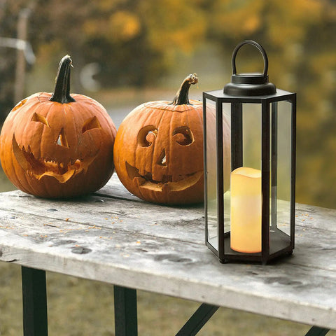 Outdoor Solar Powered Lantern With Flameless Candle 18 Inch Black Metal And Glass Waterproof Hanging Tapered Candle Lamp next to pumpkins