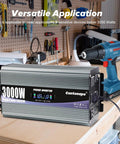 Heavy Duty 3000 Watt Power Inverter Converts 12V Dc To 120V Ac, shown with drill, in workshop setting, sleek design, LCD display.