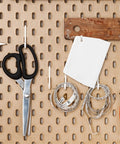 No Sweat Notched Glue Spreader Kit With Four Piece White Plastic Trowel Set Featuring Half And One Inch Teeth For Flawless Epoxy Resin Putty Application On Hardwood Flooring With Integrated Loop Handles For Quick Wall Mount And Storage tools organized on pegboard with scissors, measuring tape, and trowel.