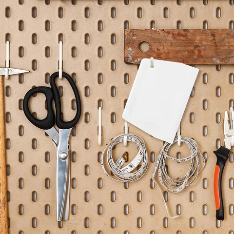 No Sweat Notched Glue Spreader Kit With Four Piece White Plastic Trowel Set Featuring Half And One Inch Teeth For Flawless Epoxy Resin Putty Application On Hardwood Flooring With Integrated Loop Handles For Quick Wall Mount And Storage tools organized on pegboard with scissors, measuring tape, and trowel.