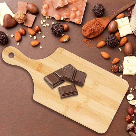 Bamboo charcuterie board with handle, 11 x 5 inches, natural finish; chocolate pieces on top.