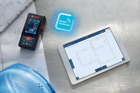 Beast Of A Blaze Outdoor Connected Laser Measure with 400 ft range displayed next to a tablet showing floor plans on a worksite table.