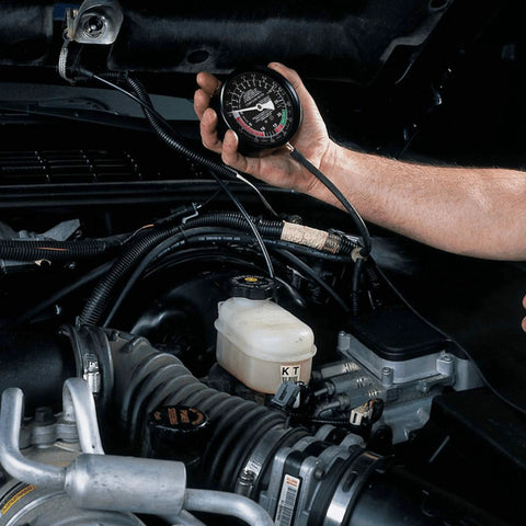 Hand-held Hromee fuel pump and vacuum tester gauge in engine bay with hoses