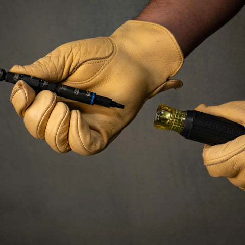 Close-up of hands with thick gloves assembling Impact Rated 11-in-1 Multi Bit Screwdriver And Nut Driver with interchangeable bits.