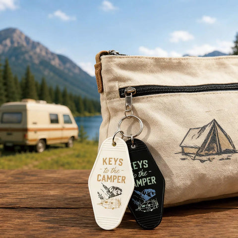 Four Piece Vintage Keychain Set For Camper RVs Retro Black And White Fobs on travel bag with RV backdrop
