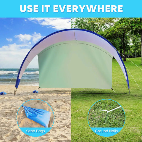 Windproof Beach Tent Sun Shelter with UPF50 Plus Protection set up on beach and grass with sandbags and ground pegs visible.