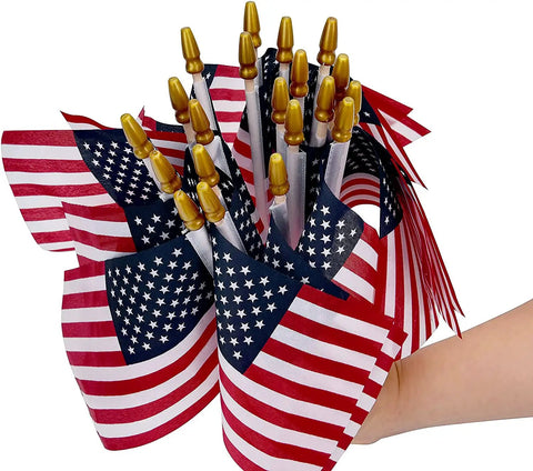 Hand holding Pack Of 100 Small 4x6 Inch American Flags On 12 Inch Wood Sticks For Outdoor Use, ideal for patriotic events.