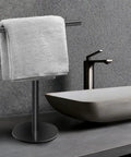 Hand Towel Holder Stand For Bathroom Vanity Countertop Matte Black Finish Free Standing Design Space Saving Movable T Shape Towel Bar Rack For Kitchen And Bath next to a modern sink.