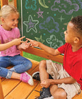 Children playing on a weatherproof wooden swing set for backyard with UV and mold protection, featuring a vinyl chalk wall.