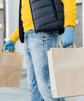 Person wearing Heavy Duty Textured Nitrile Disposable Gloves Blue Medium 3.5 Mil carrying brown paper bags.