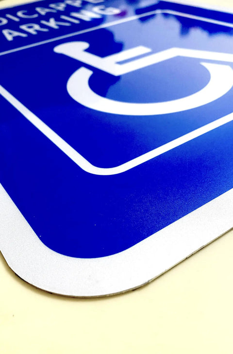 Heavy Duty Aluminum Handicap Parking Sign Ada Compliant Reflective Metal Plaque featuring rounded edges and bright blue background.