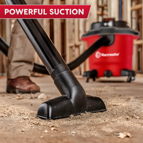 Heavy Duty 12 Gal Wet Dry Shop Vac With Beastly 5.5 Peak HP Motor And Nine Must Have Cleaning Attachments For Cranking Nasty Garage Jobs And Spills Features Classic Red Plastic Design, close-up of black nozzle on dusty floor.