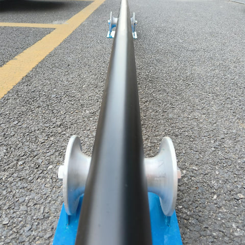 Beefy Heavy Duty Cable Puller Sheave for Large Scale Laying showing pipeline sliding over aluminum U-groove base on pavement