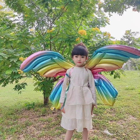 Child wearing Fairy Wing Balloon Costume Set for Halloween Party and Cosplay with rainbow foil angel butterfly wings outdoors