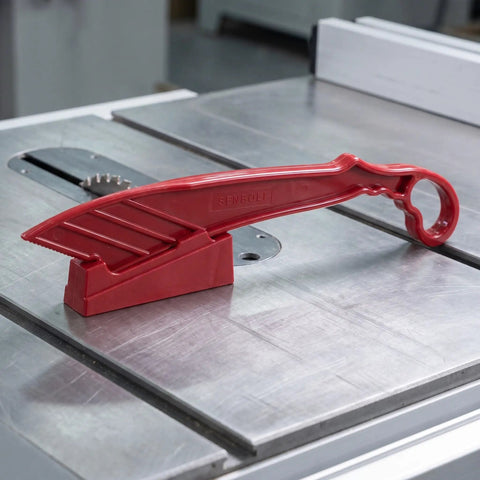 Rock Solid Table Saw Push Stick With Riving Knife Splitter 16.5 Inches Long on table saw, sturdy red plastic construction.