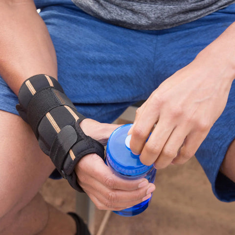 Unisex Fingerless Wrist Wrap With Ice Pack And Heat Therapy worn on right hand opening a water bottle, adjustable compression support, black.