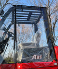 All Weather Forklift Cab Enclosure Cover With Heavy Duty UV Protection And Waterproof Vinyl Universal Fit For Forklifts Up To 6000 Lb Easy Zip Access Keeps Cold Air Rain Snow Out. Image showing a transparent cab cover fitted on a red forklift.