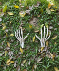 Left And Right Skeleton Hands 8 Inch Spooky Bones Halloween Decor on grass covered with leaves.