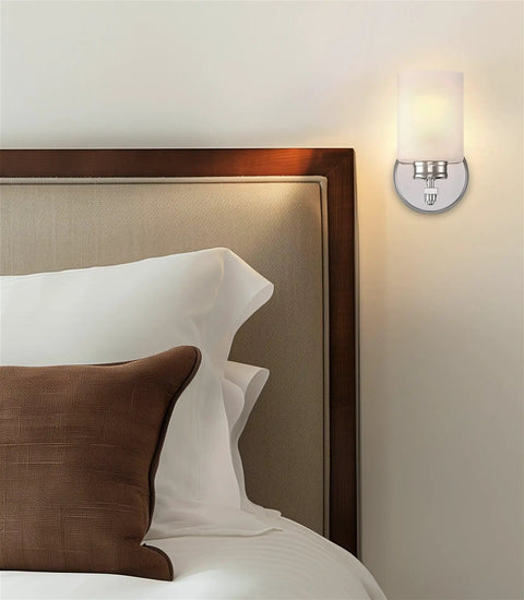 Kira Home Phoebe 8" Modern Industrial Wall Sconce for Bathroom Vanity, Pack of 2 mounted beside a bed, chrome finish with frosted glass.
