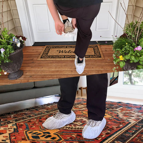 Person wearing Disposable Shoe Covers Pack Of 200 100 Pairs Built Tough Waterproof Non Slip Boot Covers indoors and outdoors