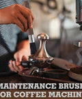 Barista cleaning brush with wooden handle and black boar bristles being used on a shiny espresso machine component