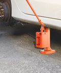 Heavy Duty Hydraulic Toe Jack 10 Ton Lift Capacity positioned under a car wheel for easy vehicle lifting in garages.