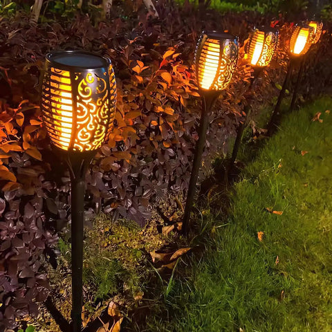 4 Pack Solar Torch Lights With Flickering Flame, outdoor waterproof stake lights illuminating a garden path