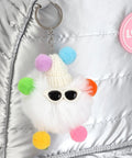 Close-up of a silver backpack with a colorful pompom keychain and love badge. 17 Inch Water Resistant Wheeled Laptop Backpack With Convertible Rolling Bag Design Full Size Laptop Compartment TSA Friendly Lightweight Travel And College Bag For Men Women Adults Overnight Trips Beautiful Silver.