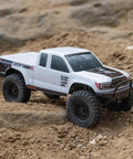 SCX24 Base Camp 4x4 Rock Crawler Ready To Run RC Truck on rocky terrain, 1/24 scale, white body, thick tires, detailed grille