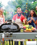 Group enjoying BBQ with Grill Table Cart For 22 Inch And 18 Inch Original Kettle Charcoal Grills, Outdoor Stand visible.