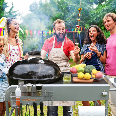 Group enjoying BBQ with Grill Table Cart For 22 Inch And 18 Inch Original Kettle Charcoal Grills, Outdoor Stand visible.