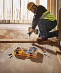 DEWALT 40-piece steel screwdriver bit set in yellow case; construction worker uses cordless drill.
