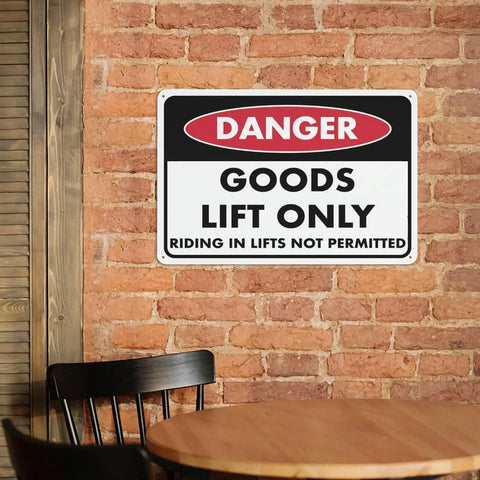 Danger sign 'Goods Lift Only' mounted on a brick wall near a wooden table.