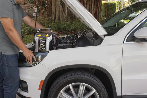 Man using 1000 Peak Amp Jump Starter With USB Power And 12V Outlet Portable Car Battery Booster On The Go With 120 PSI Tire Inflator