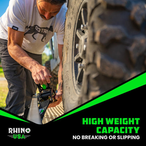 Man securing tire with Beefy Heavy Duty Self Retracting Ratchet Straps 2 Inch By 10 Feet With 3033 Pound Break Strength for truck