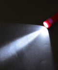 Red flashlight from 18 Pack 9 LED Mini Flashlights With AAA Batteries Included And Pre Installed, illuminating a dark surface.
