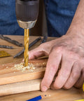Cobalt left-hand drill bit, TiN-coated gold bit drilling into wood