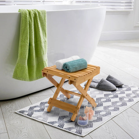 Foldable Shower Stool For Tiny Bathrooms Bamboo Foot Rest And Shaving Stool beside bathtub on bathroom rug.