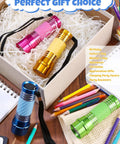 Four Pack High Power Glow In Dark Mini LED Flashlights Aluminum Body in assorted colors on a table with stationery.