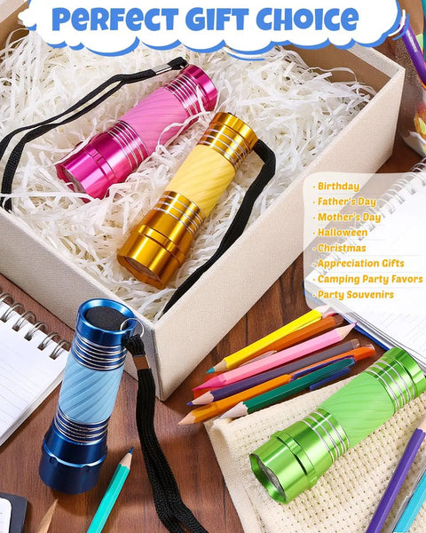 Four Pack High Power Glow In Dark Mini LED Flashlights Aluminum Body in assorted colors on a table with stationery.