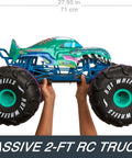Hands holding Mega-Wrex 1 To 6 Scale RC Monster Truck with extra large tires, 2 feet long, showcasing its size and ruggedness.