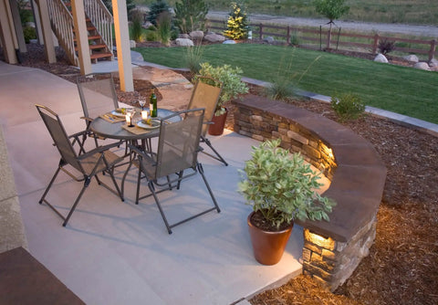 Garden patio with 8-Pack 4-Inch LED Hardscape Lights for Pavers and Walls, 2W 2700K Warm White Outdoor Step Lighting on stone wall.