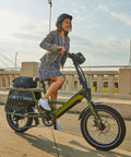 Person riding green e-bike with Two Pack Beefy 20x3 E-Bike Inner Tubes For Fat Tires 64/76-406 AV32mm Schrader Valve on city bridge.