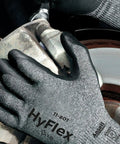 Close-up of HyFlex 11-801 Nylon Glove With Black Foam Nitrile Coating and Knit Wrist Cuff in use on automotive part