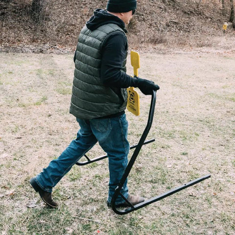 Person carrying AR500 Dual Spinner Target for rifle shooting, collapsible stand for easy transport, three eighths inch steel target