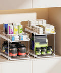 Super Handy Two Tier Under Sink Organizers And Bathroom Storage Solutions For Cabinets And Kitchen Pantries With Smooth Slide Out Drawers And Fully Adjustable Dividers In Bright White Two Pack with various jars and boxes.