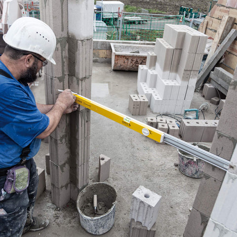 Worker using Extendable 36 Inch Level With Locking Design And Continuous Marking Edge Type 80T for precise wall alignment.