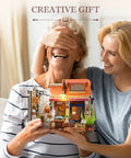 Two people smiling with DIY Miniature Bookstore Kit 1 To 20 Scale With LED Lights Build Your Own Tiny House Craft Kit