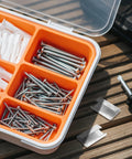 Open box of screws and plastic anchors beside a screwdriver on wooden table